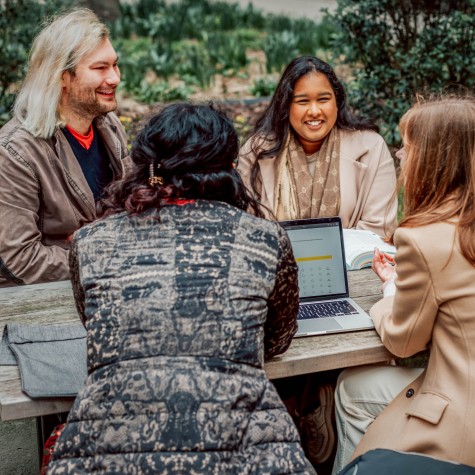 Vier Studierende sitzen im Innenhof und unterhalten sich